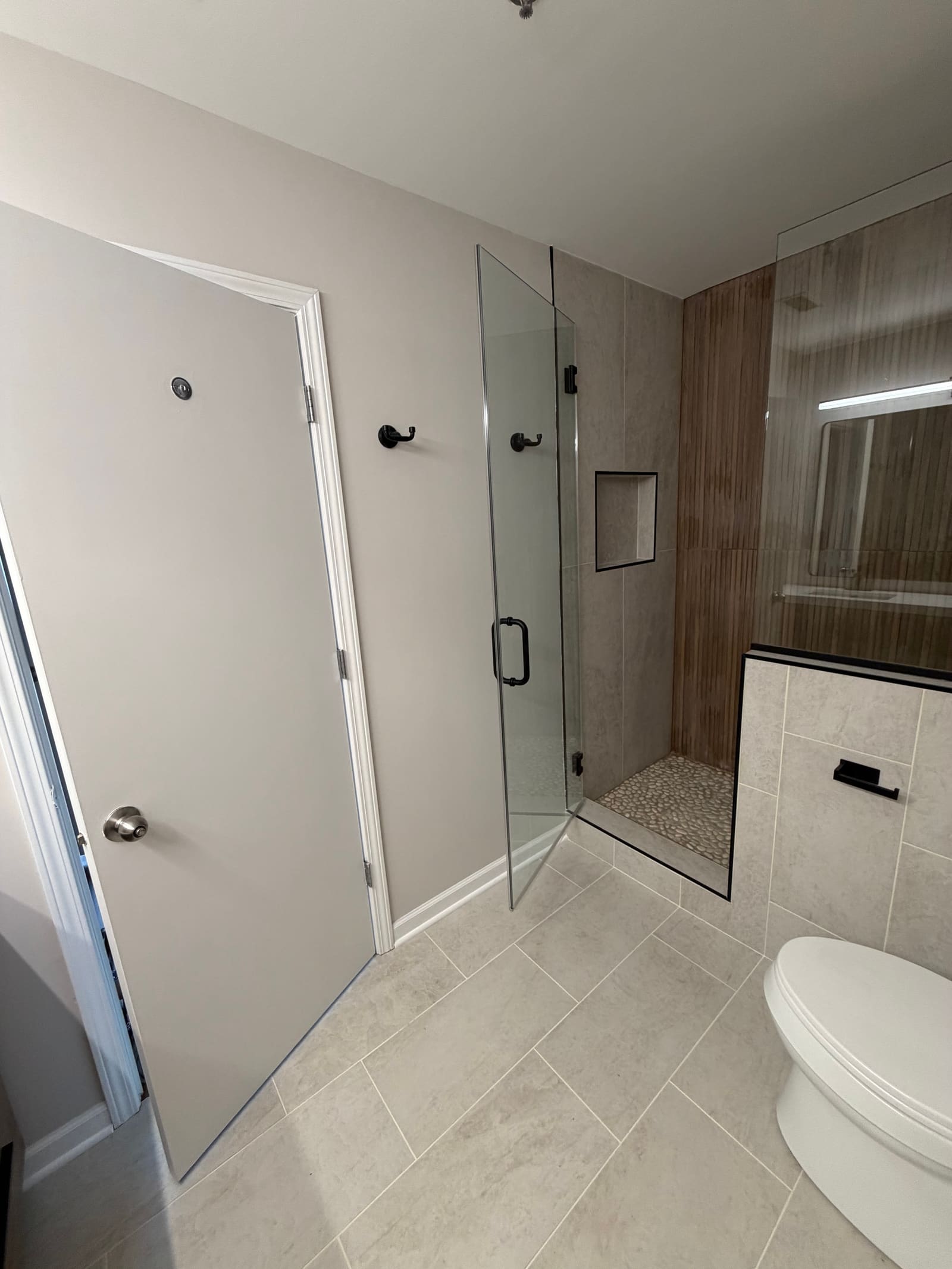 View toward the shower showing the recessed wall niche and large-format floor tile.